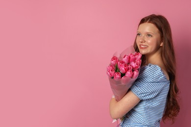 Photo of Beautiful teenage girl with bouquet of tulips on pink background, space for text