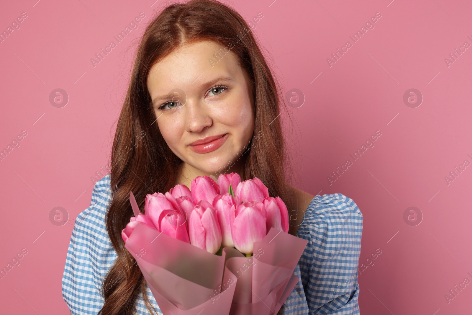 Photo of Beautiful teenage girl with bouquet of tulips on pink background