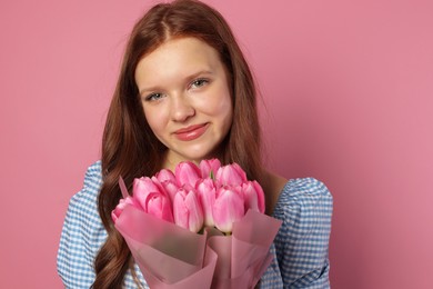 Photo of Beautiful teenage girl with bouquet of tulips on pink background