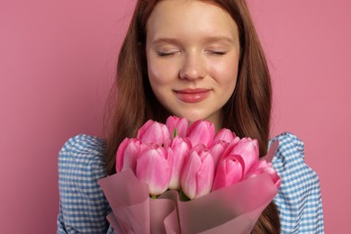 Photo of Beautiful teenage girl with bouquet of tulips on pink background