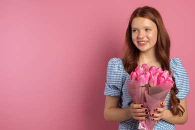 Photo of Beautiful teenage girl with bouquet of tulips on pink background, space for text