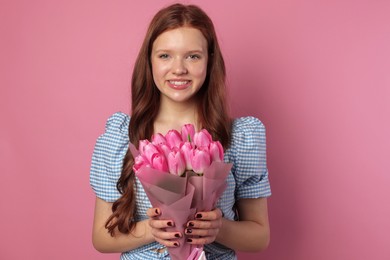 Photo of Beautiful teenage girl with bouquet of tulips on pink background