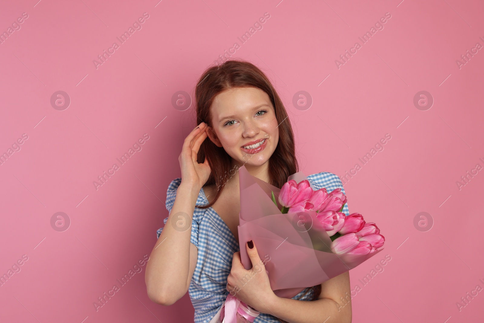 Photo of Beautiful teenage girl with bouquet of tulips on pink background