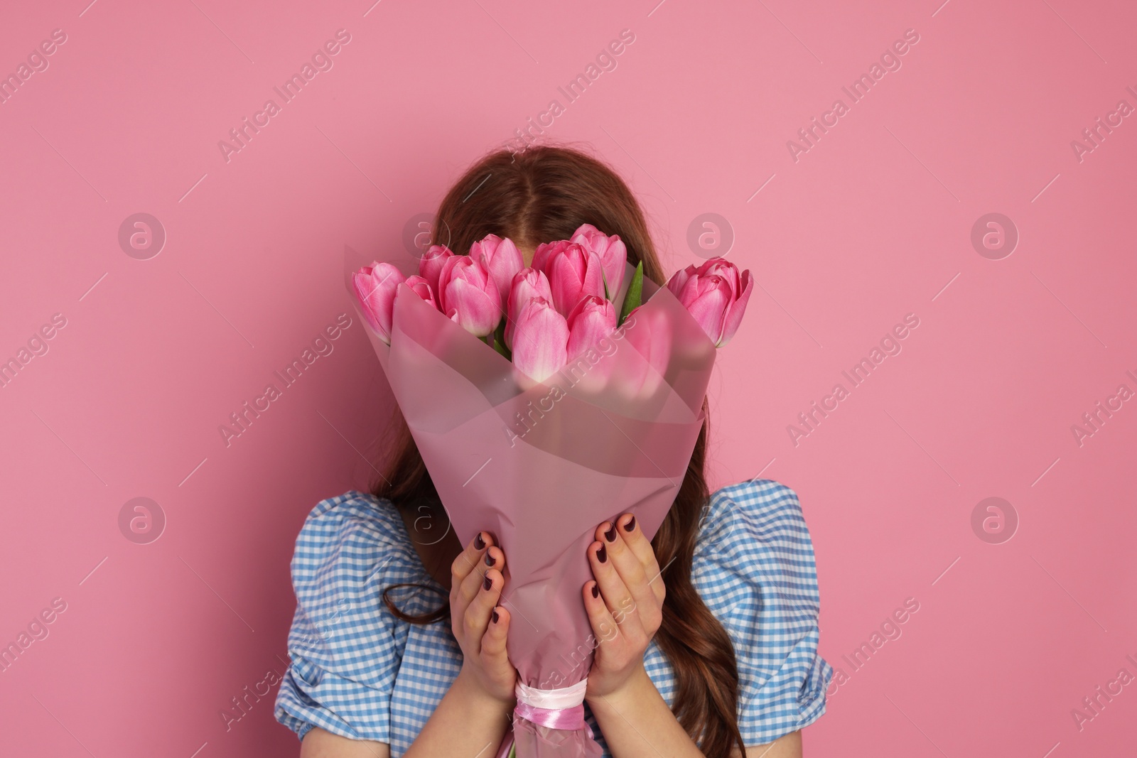 Photo of Teenage girl with bouquet of tulips on pink background