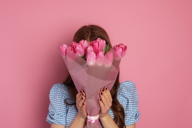 Photo of Teenage girl with bouquet of tulips on pink background