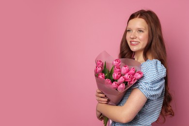 Photo of Beautiful teenage girl with bouquet of tulips on pink background, space for text