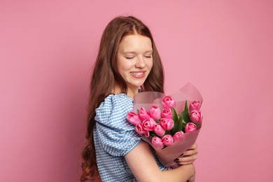 Photo of Beautiful teenage girl with bouquet of tulips on pink background