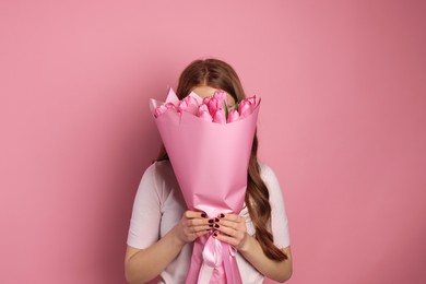 Photo of Beautiful teenage girl with bouquet of tulips on pink background