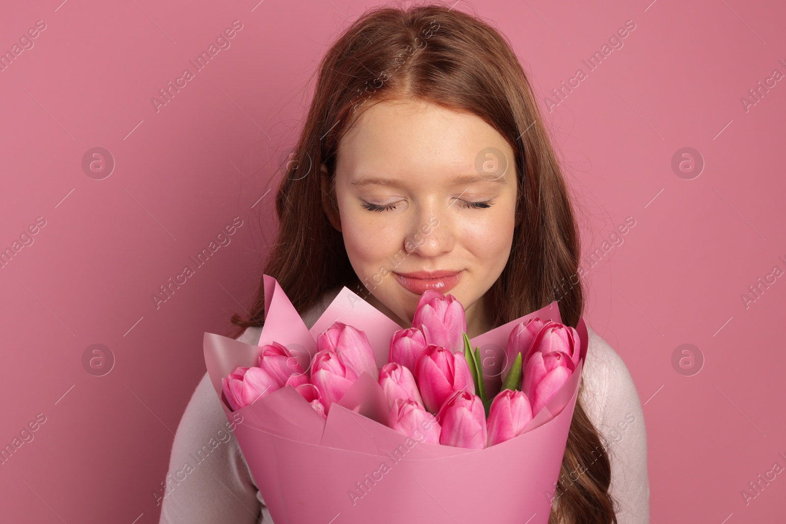 Photo of Beautiful teenage girl with bouquet of tulips on pink background