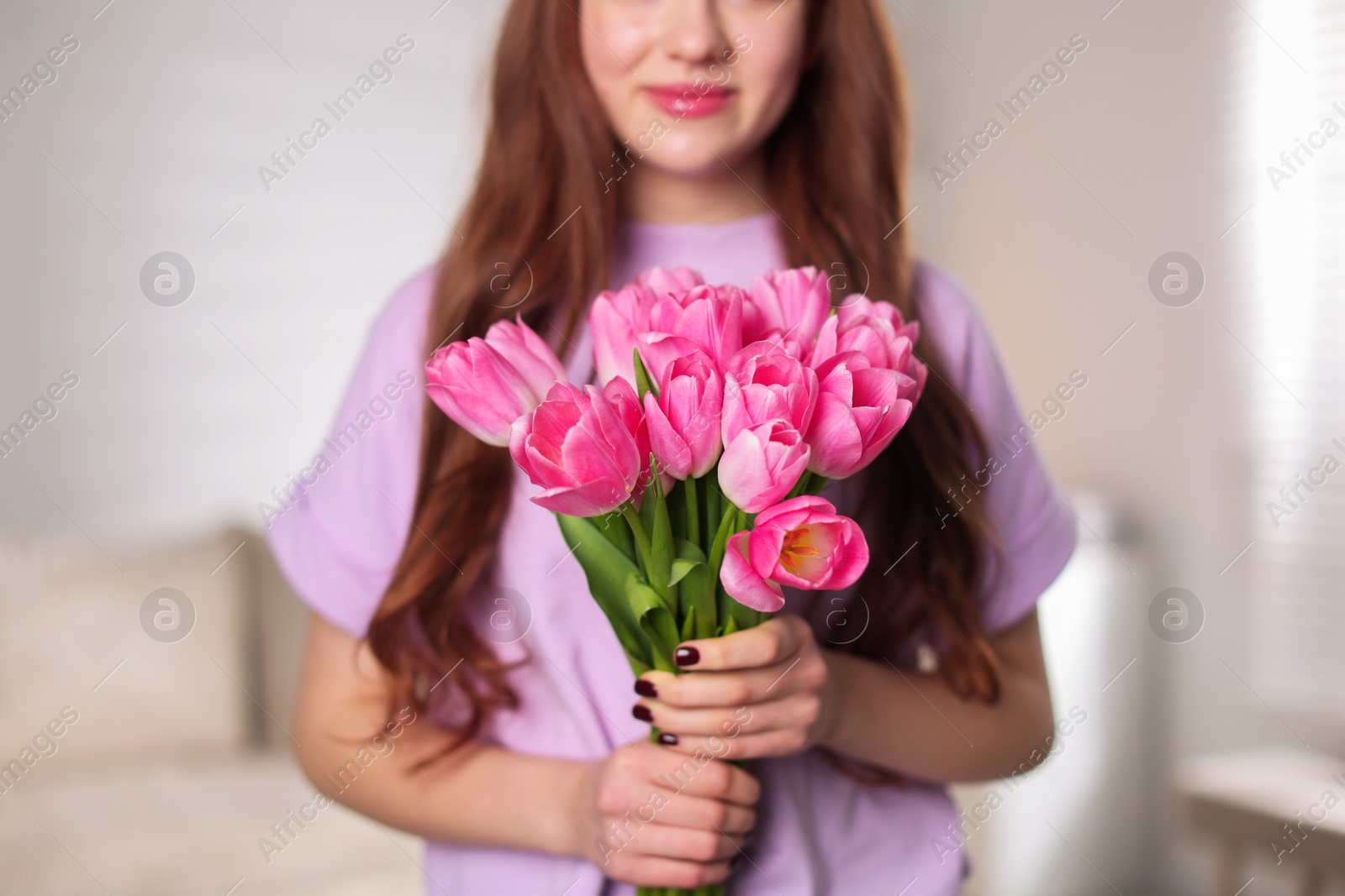 Photo of Teenage girl with bouquet of tulips indoors, closeup