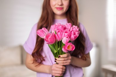 Photo of Teenage girl with bouquet of tulips indoors, closeup