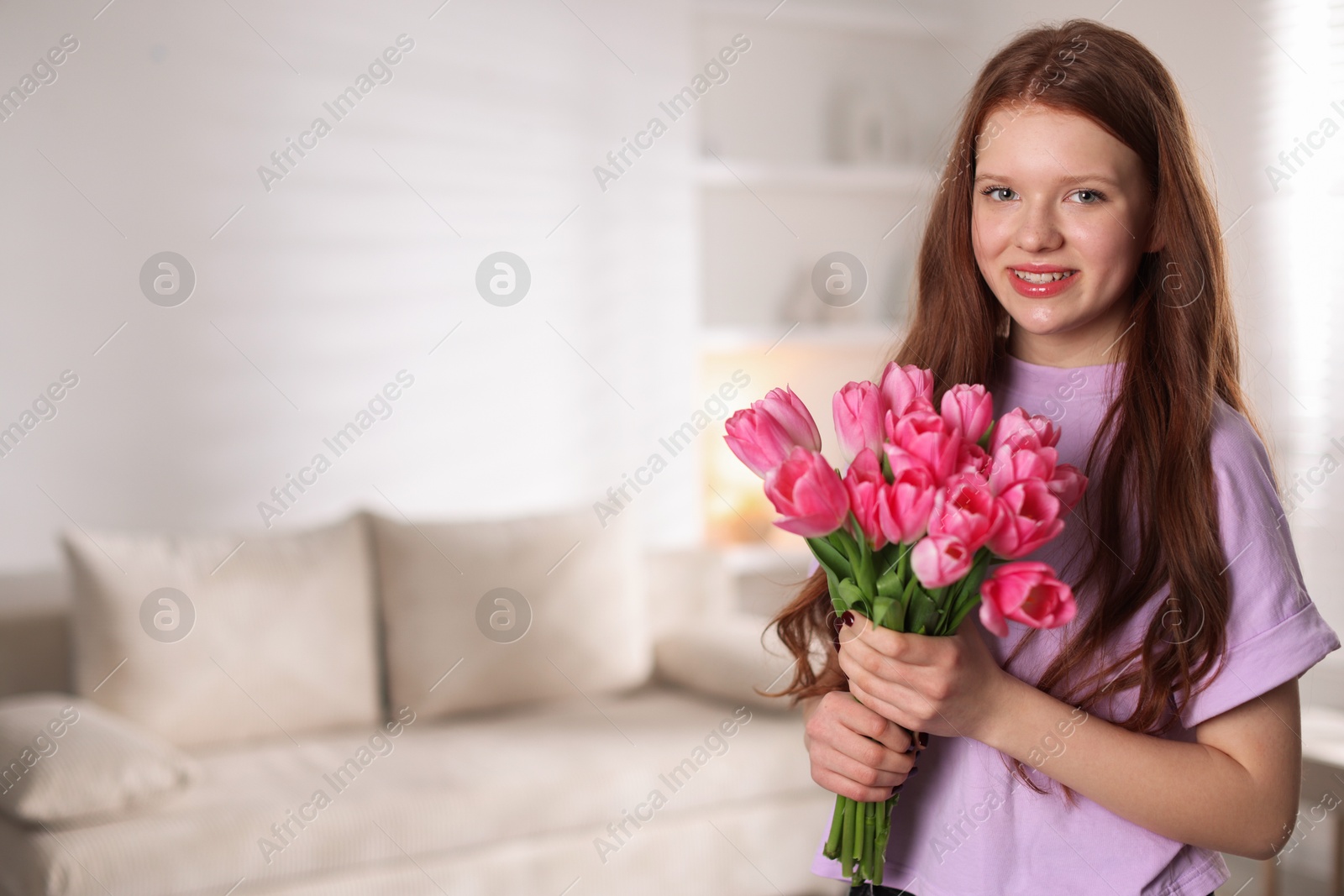 Photo of Beautiful teenage girl with bouquet of tulips indoors, space for text