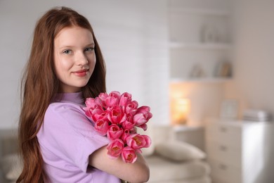 Photo of Beautiful teenage girl with bouquet of tulips indoors, space for text