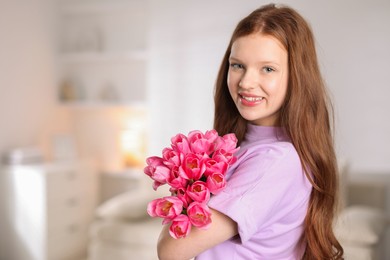 Photo of Beautiful teenage girl with bouquet of tulips indoors, space for text