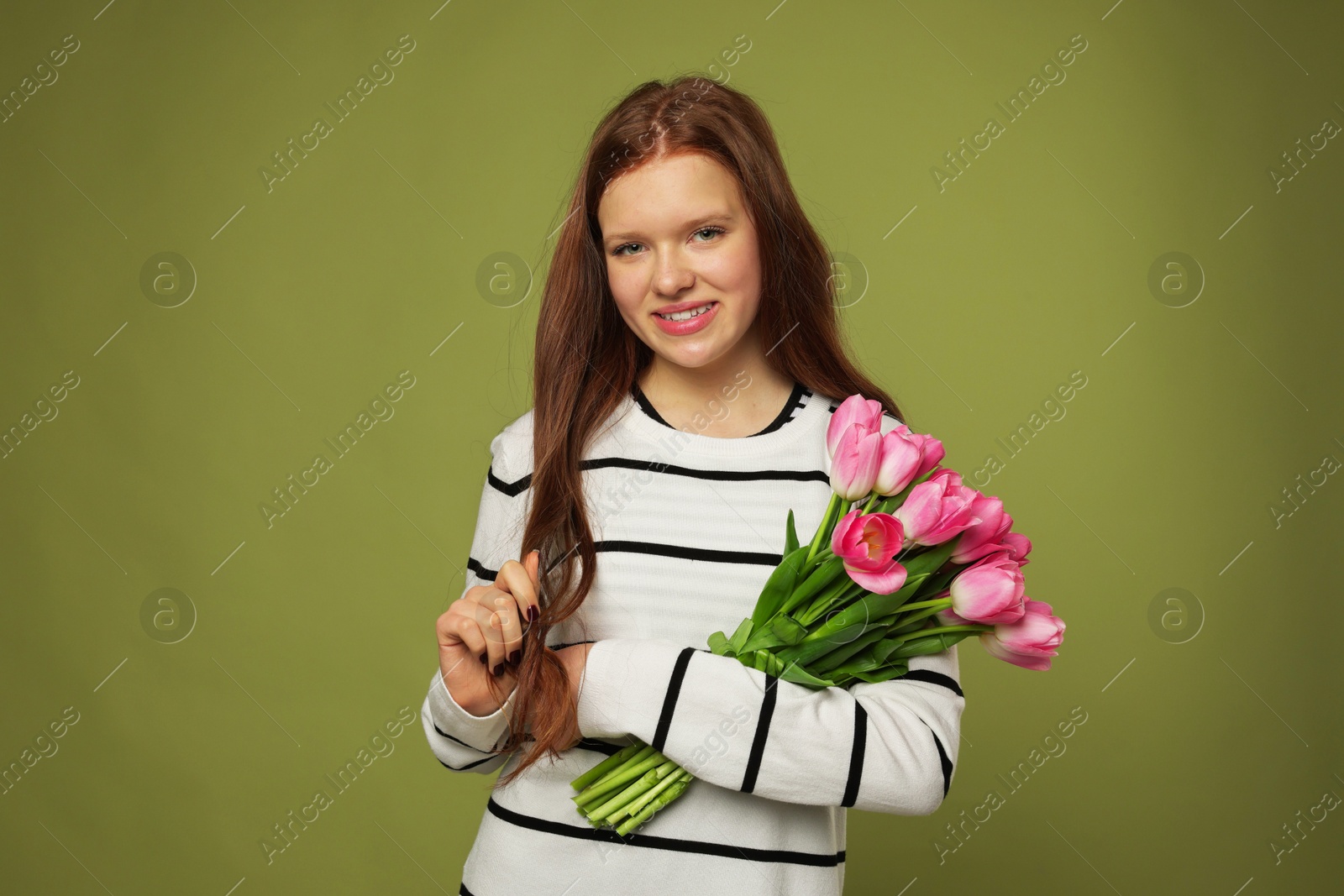 Photo of Beautiful teenage girl with bouquet of tulips on olive background