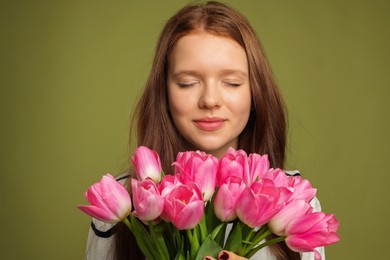 Photo of Beautiful teenage girl with bouquet of tulips on olive background