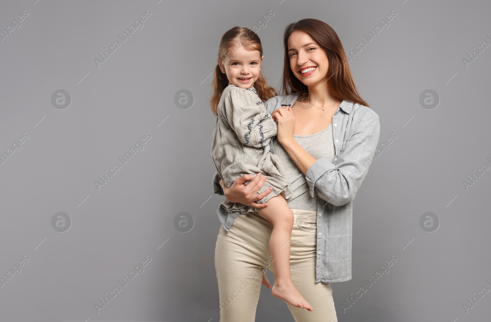 Photo of Portrait of happy mother with her cute little daughter on grey background