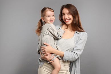 Photo of Portrait of happy mother with her cute little daughter on grey background