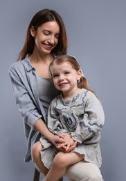 Photo of Happy mother with her cute little daughter on grey background