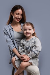 Photo of Happy mother with her cute little daughter on grey background