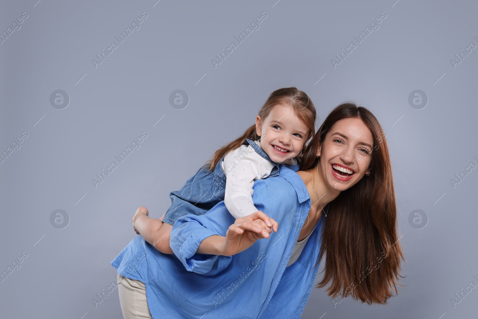 Photo of Portrait of happy mother with her cute little daughter on grey background