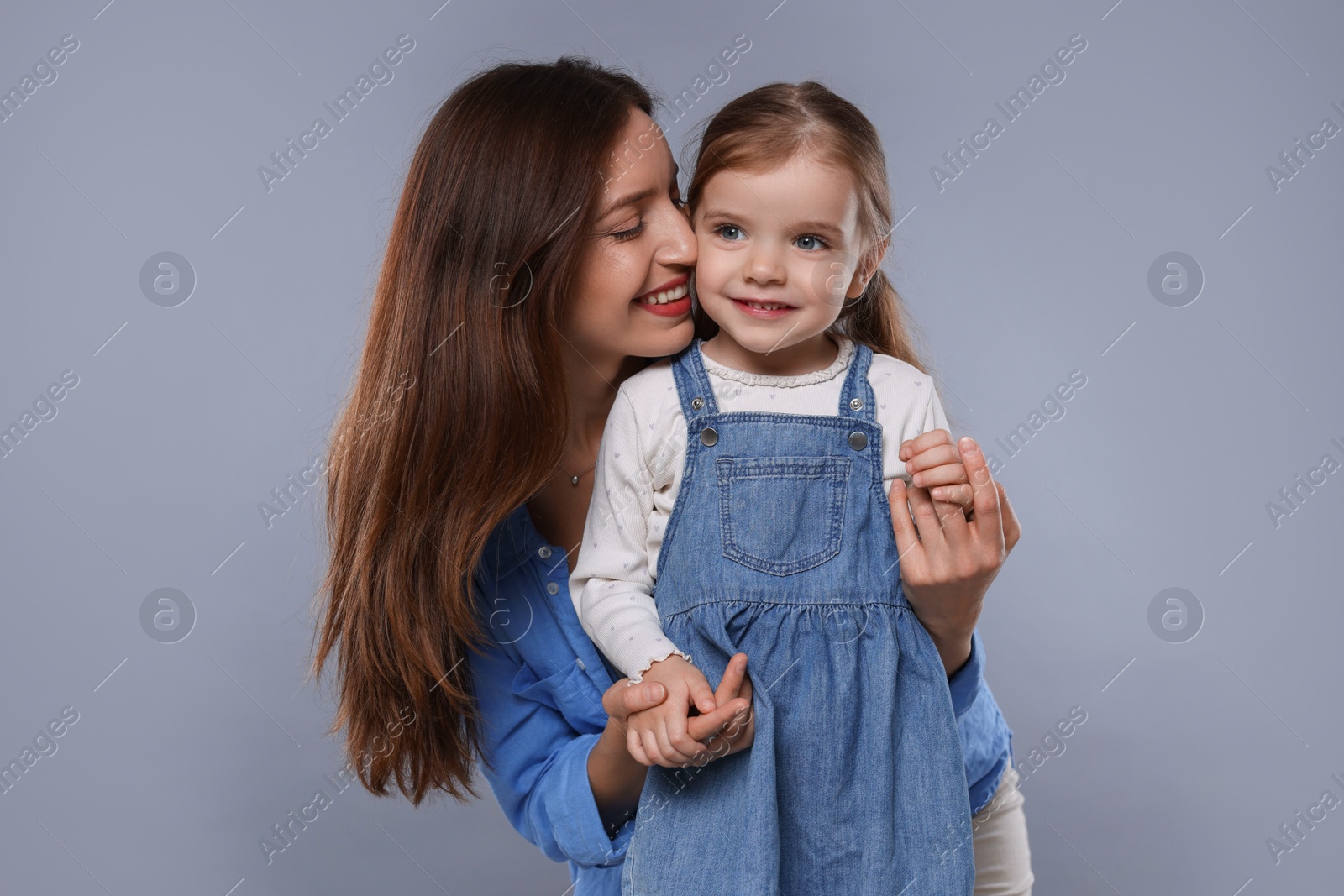 Photo of Happy mother with her cute little daughter on grey background