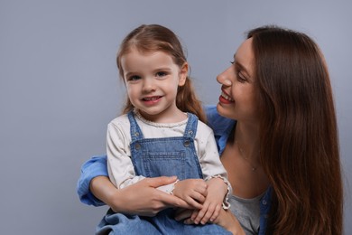 Photo of Happy mother with her cute little daughter on grey background