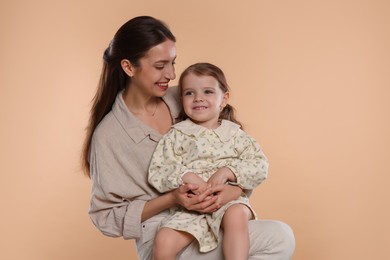 Photo of Happy mother with her cute little daughter on beige background