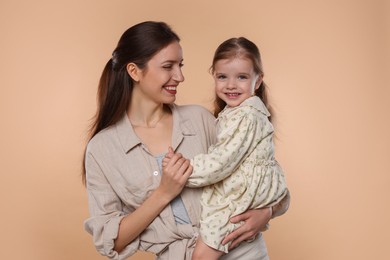 Photo of Happy mother with her cute little daughter on beige background