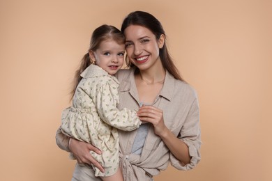 Photo of Portrait of happy mother with her cute little daughter on beige background