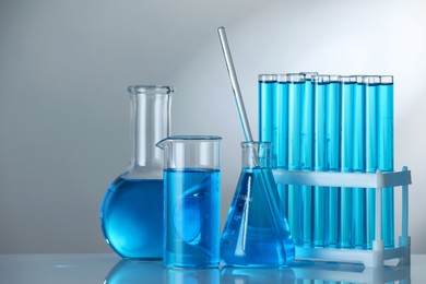 Photo of Laboratory glassware with blue liquid on mirror surface against grey background