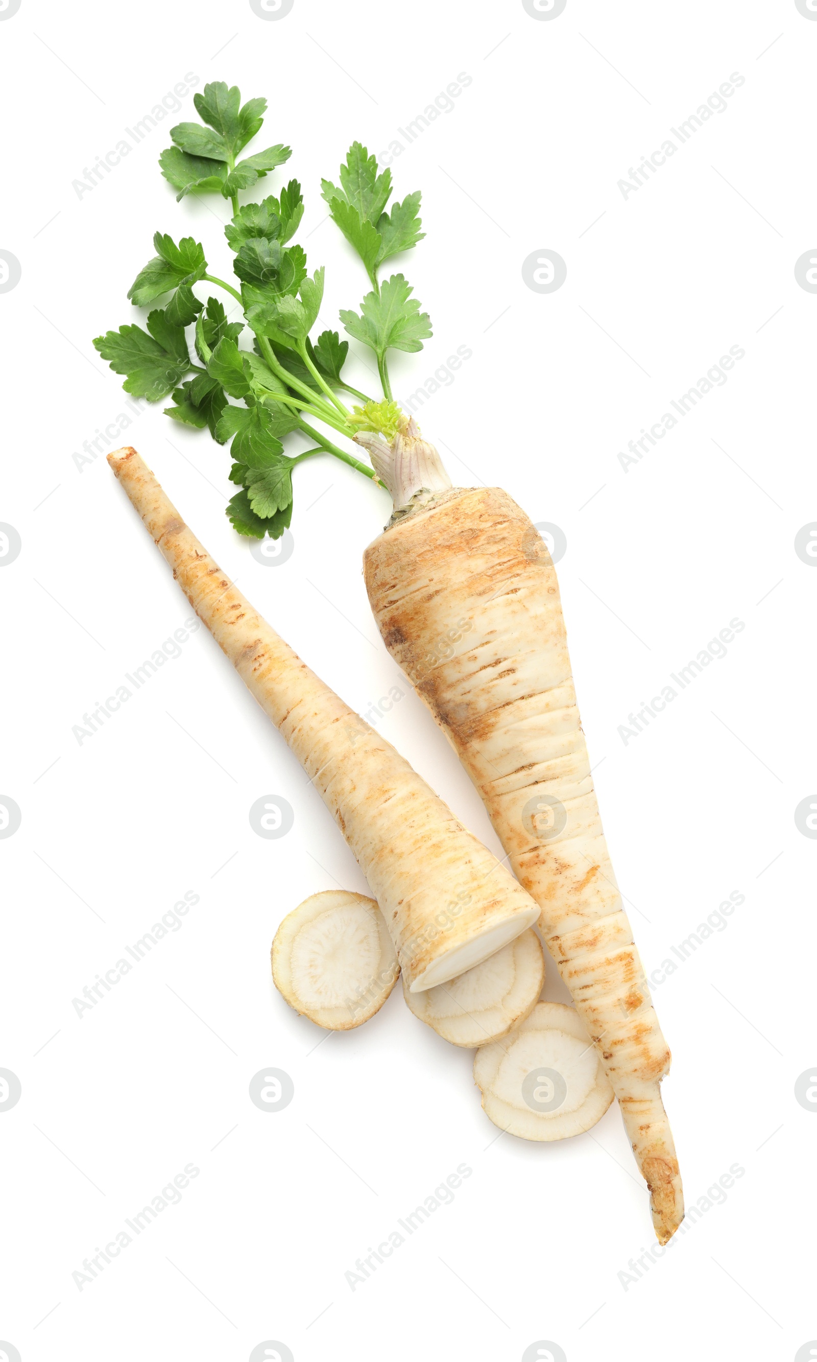 Photo of Whole and cut fresh parsley roots isolated on white, top view