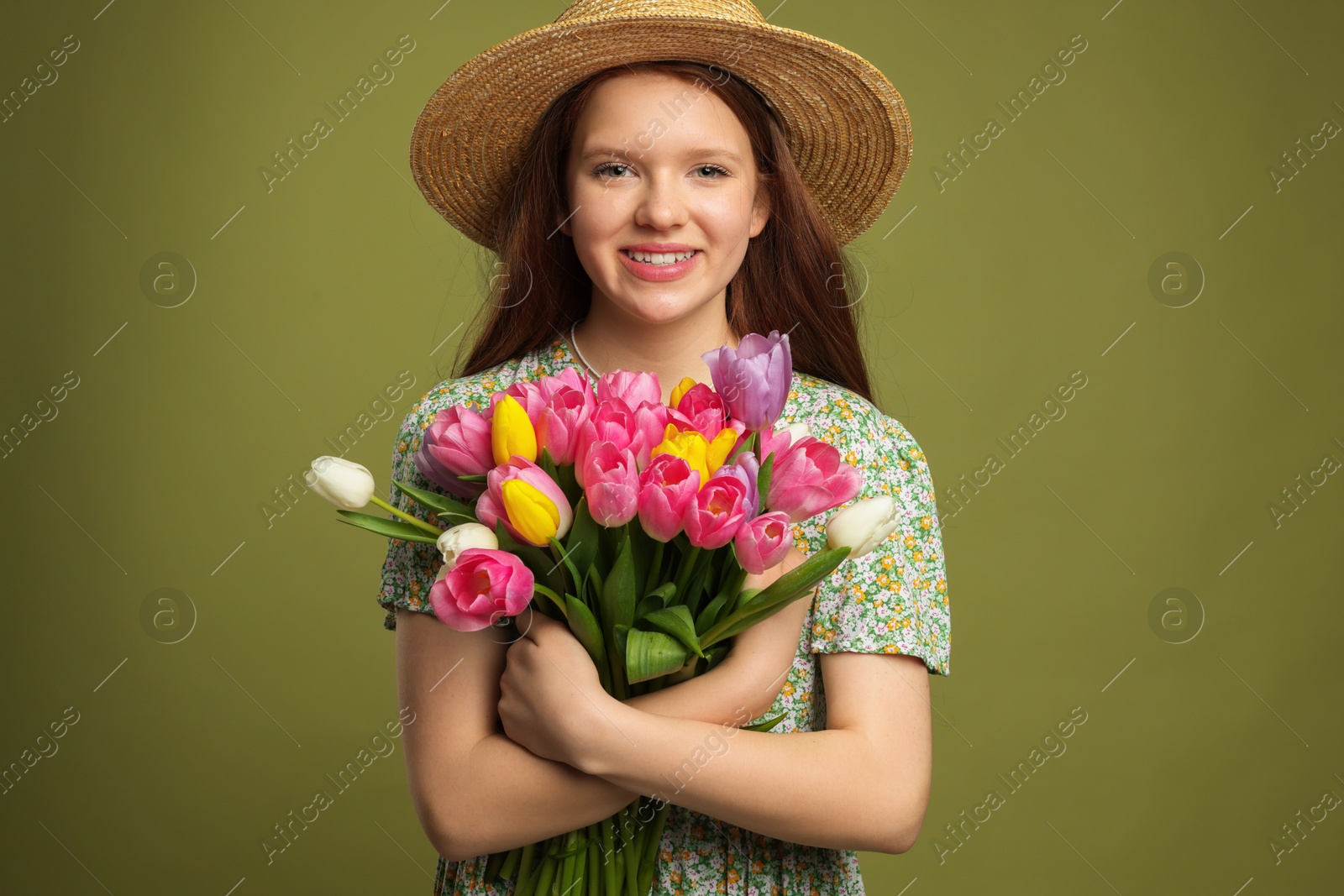 Photo of Beautiful teenage girl with bouquet of tulips on olive background