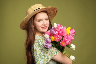 Photo of Beautiful teenage girl with bouquet of tulips on olive background