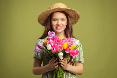 Photo of Beautiful teenage girl with bouquet of tulips on olive background