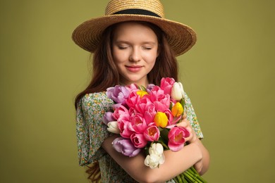 Photo of Beautiful teenage girl with bouquet of tulips on olive background