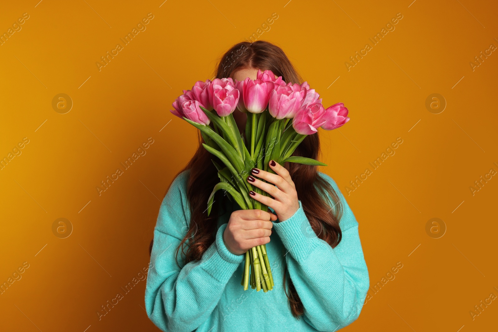 Photo of Teenage girl with bouquet of tulips on orange background