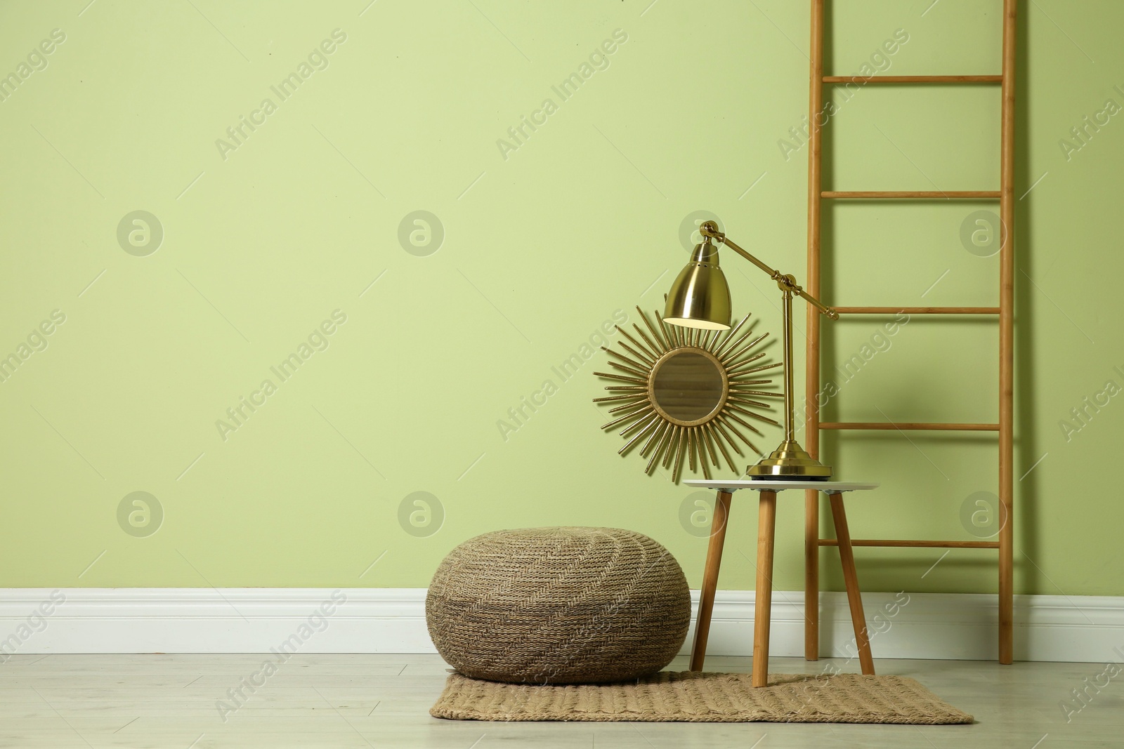 Photo of Stylish room interior with comfortable knitted pouf and decor elements near light green wall, space for text