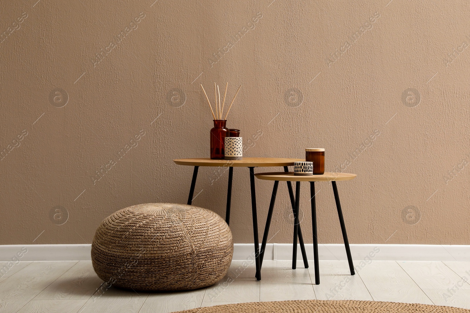 Photo of Knitted pouf and decor elements near beige wall indoors. Space for text