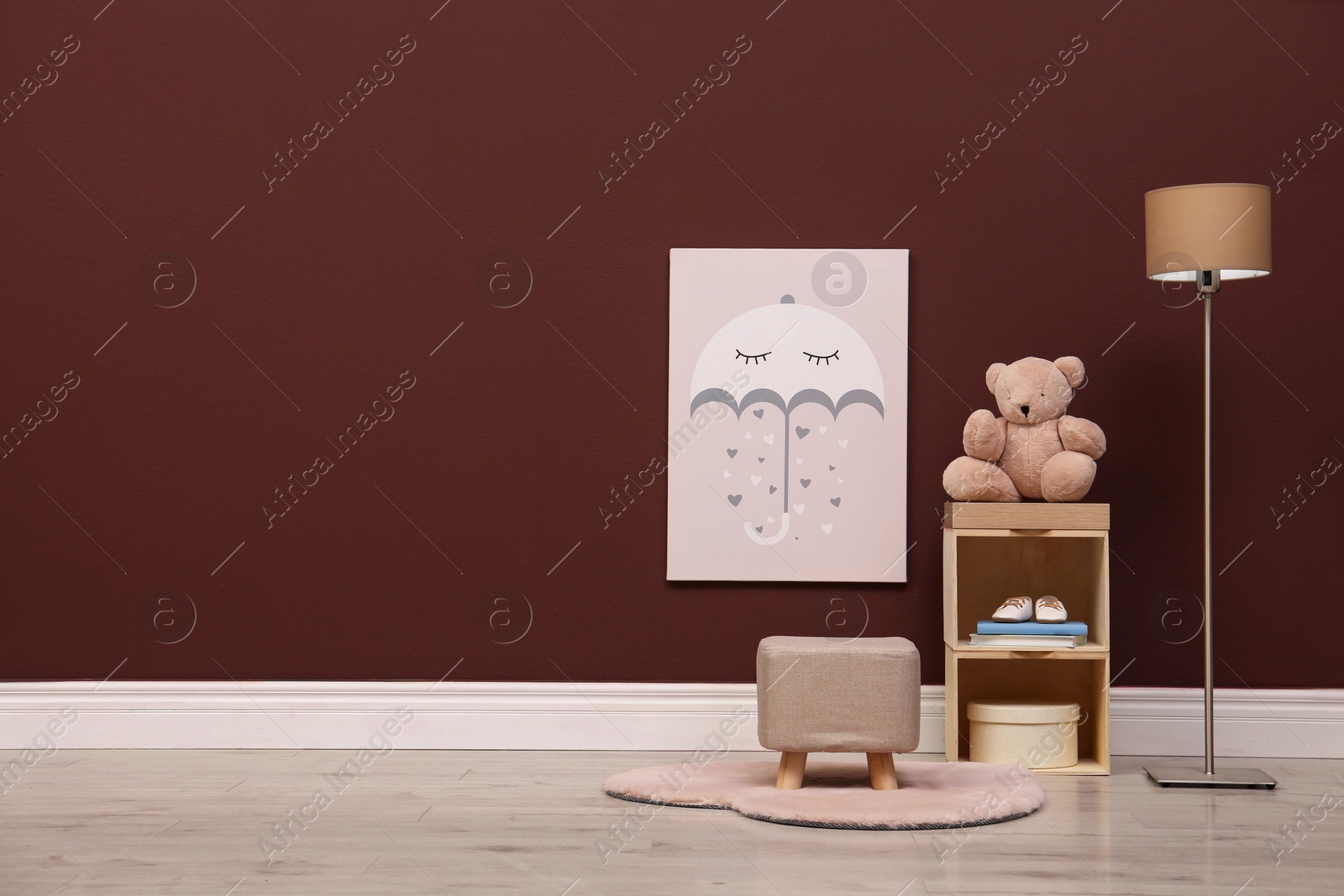 Photo of Stylish beige ottoman, shelving unit with toy bear and lamp in room. Space for text