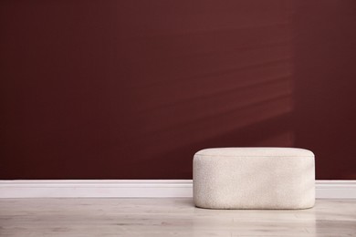 Photo of Stylish beige ottoman near brown wall indoors