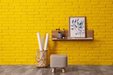 Photo of Stylish pouf near yellow brick wall indoors. Interior design