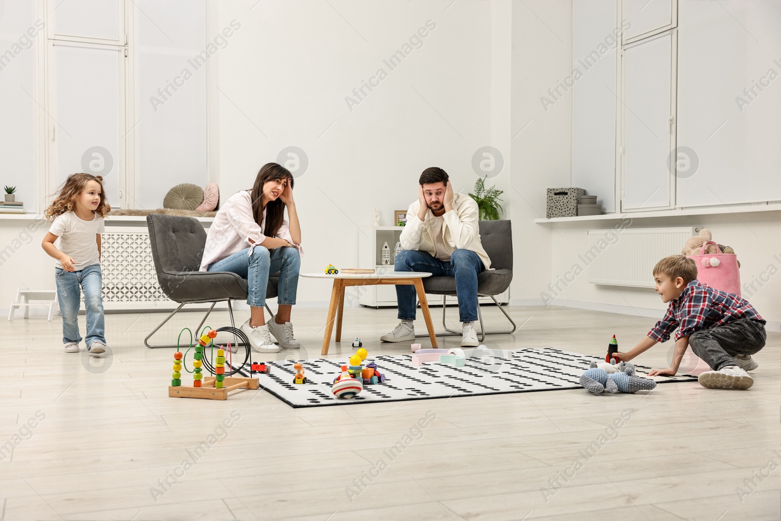 Photo of Hyperactive children playing and their overwhelmed parents at home