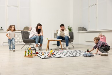 Photo of Hyperactive children playing and their overwhelmed parents at home