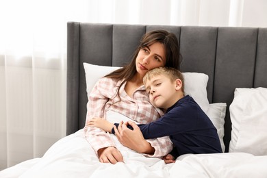 Photo of Overwhelmed mother with her son in bed at home