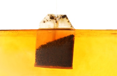 Photo of Putting tea bag into glass cup on white background, closeup