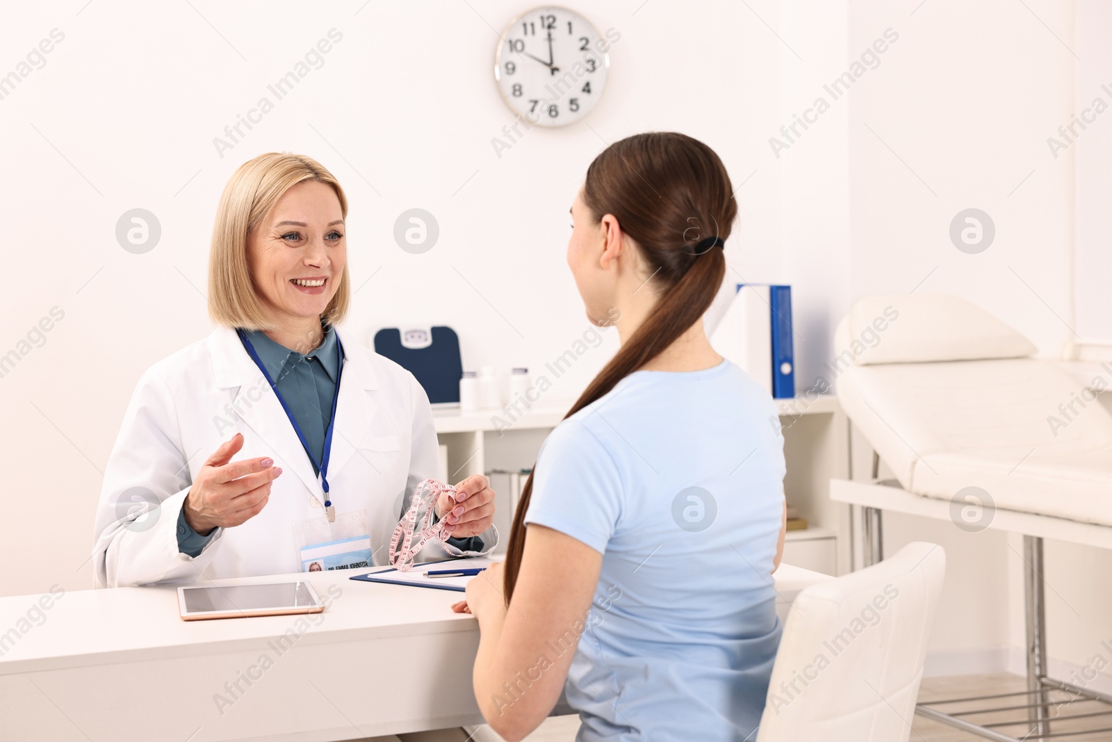 Photo of Weight loss. Smiling nutritionist consulting patient at table in clinic