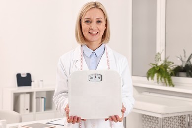 Photo of Weight loss. Happy nutritionist with scales in clinic