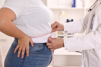 Photo of Weight loss. Nutritionist measuring patient's waist with tape in clinic, closeup