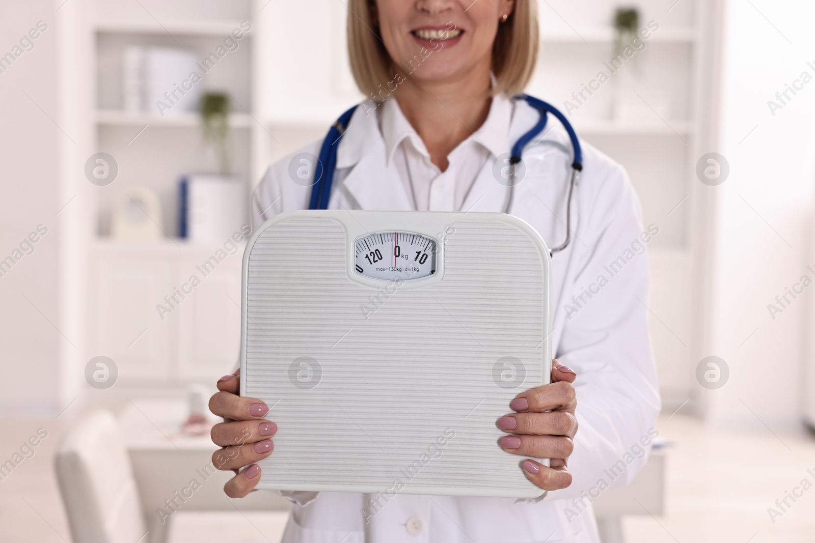 Photo of Weight loss. Smiling nutritionist with scales in clinic, closeup